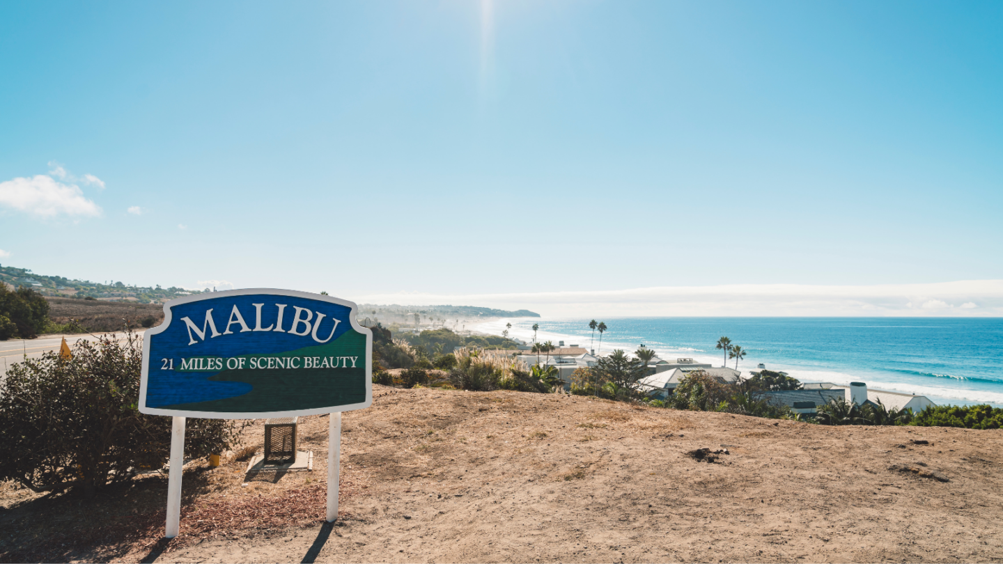blue welcome sign that says malibu 21 miles of scenic beauty